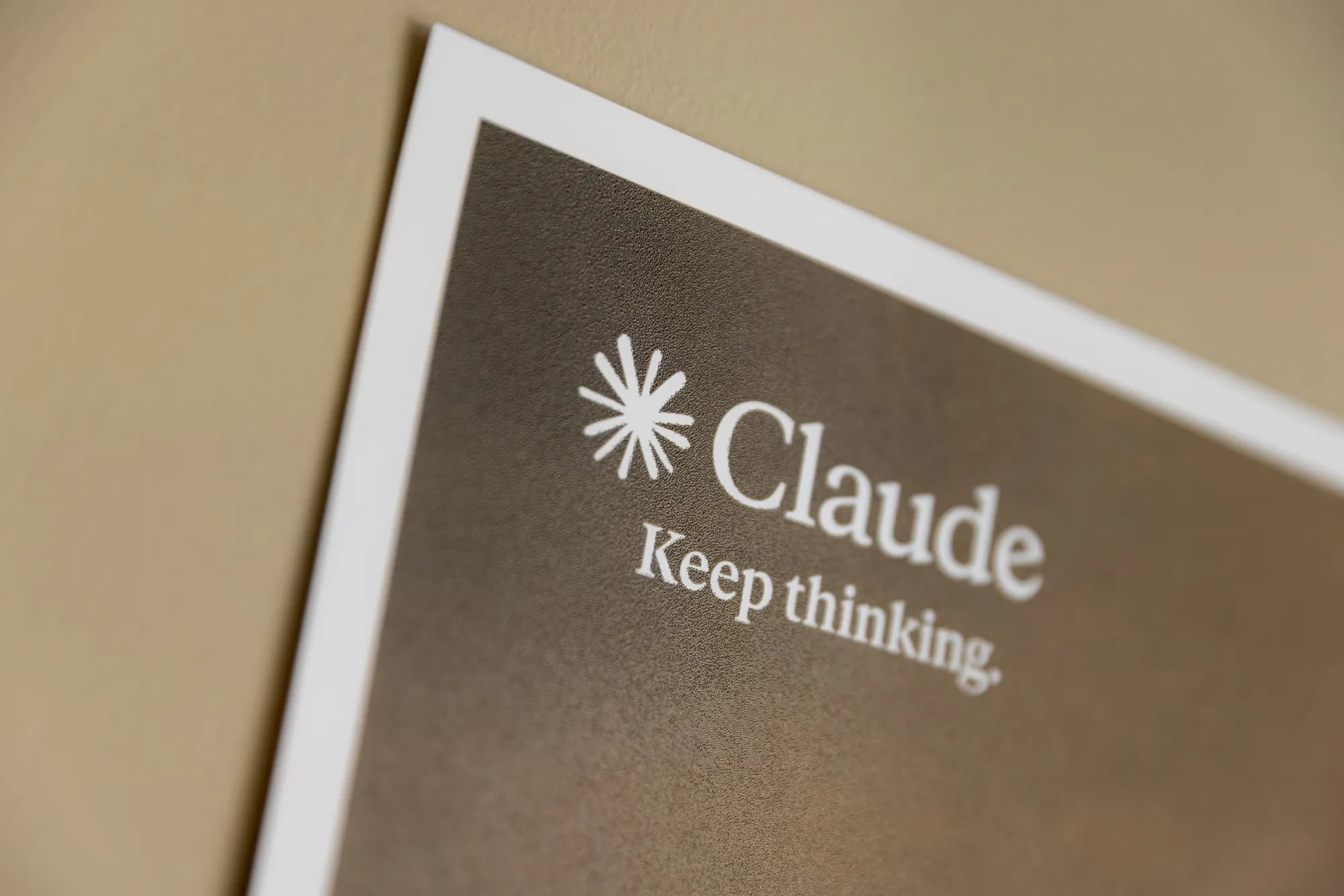 A close-up of a framed Claude by Anthropic sign reading 'Keep thinking'