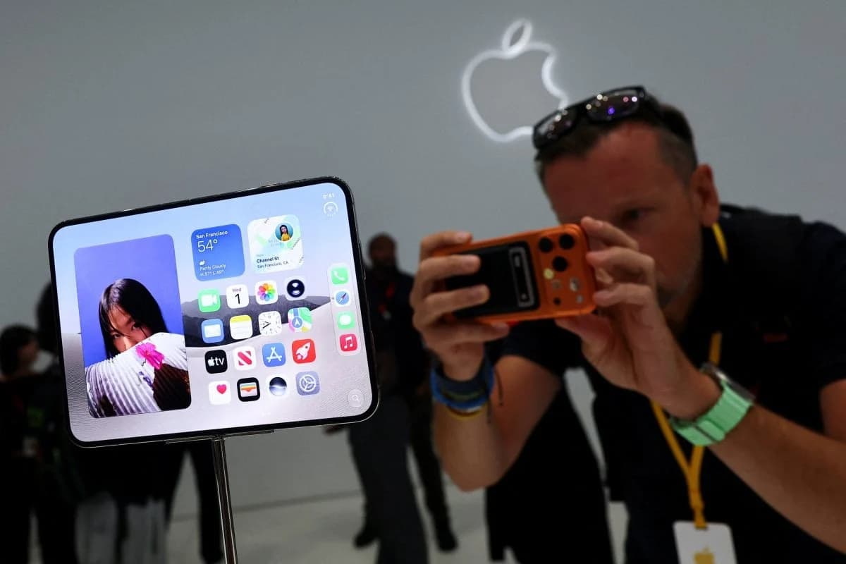 A man photographing a foldable iPhone display at an Apple store