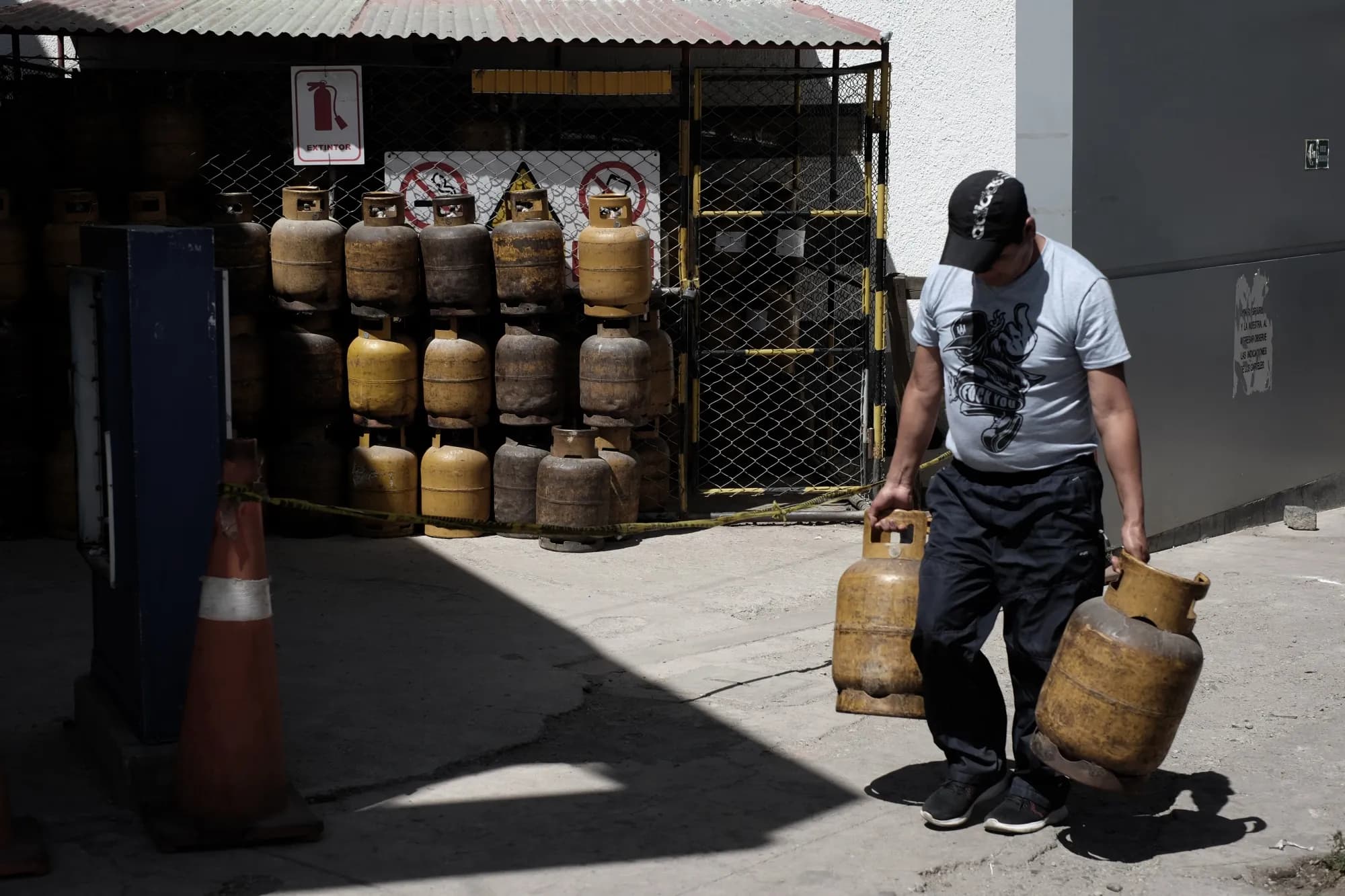 Stacked propane gas cylinders behind a fenced depot in Bolivia