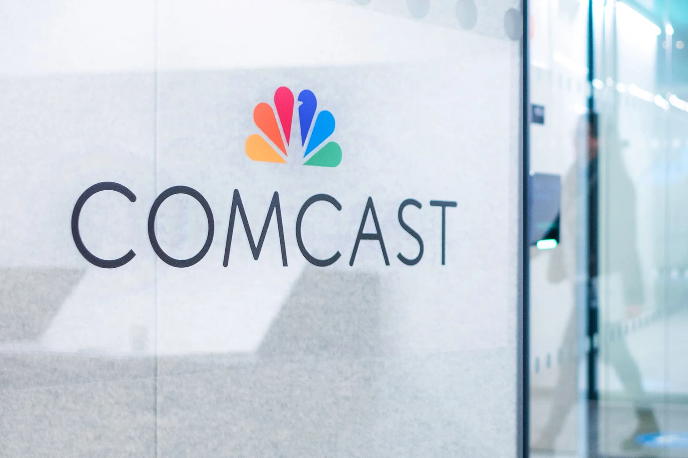 The Comcast logo on a glass office wall