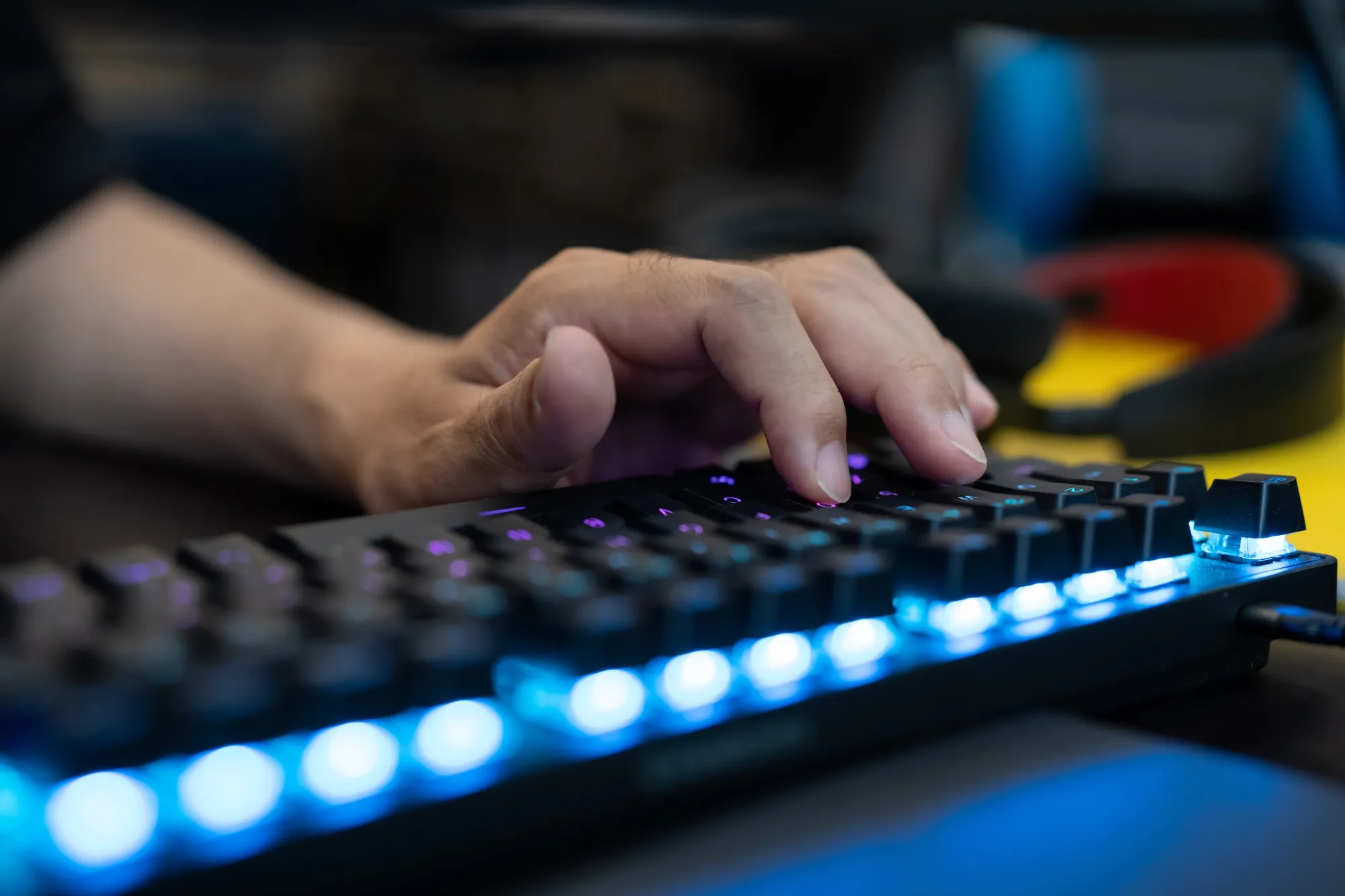 A trader's hand on a backlit mechanical keyboard in front of trading screens