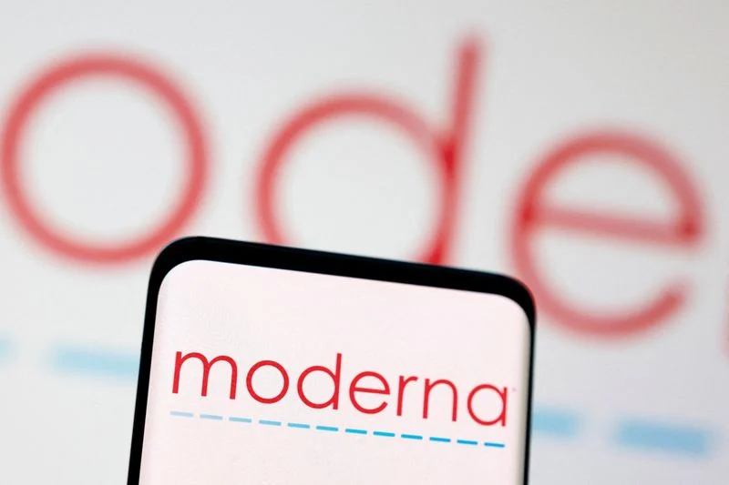 A smartphone displaying the Moderna logo in front of a blurred Moderna wordmark