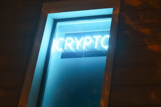 A glowing neon 'Crypto' sign in a dark doorway