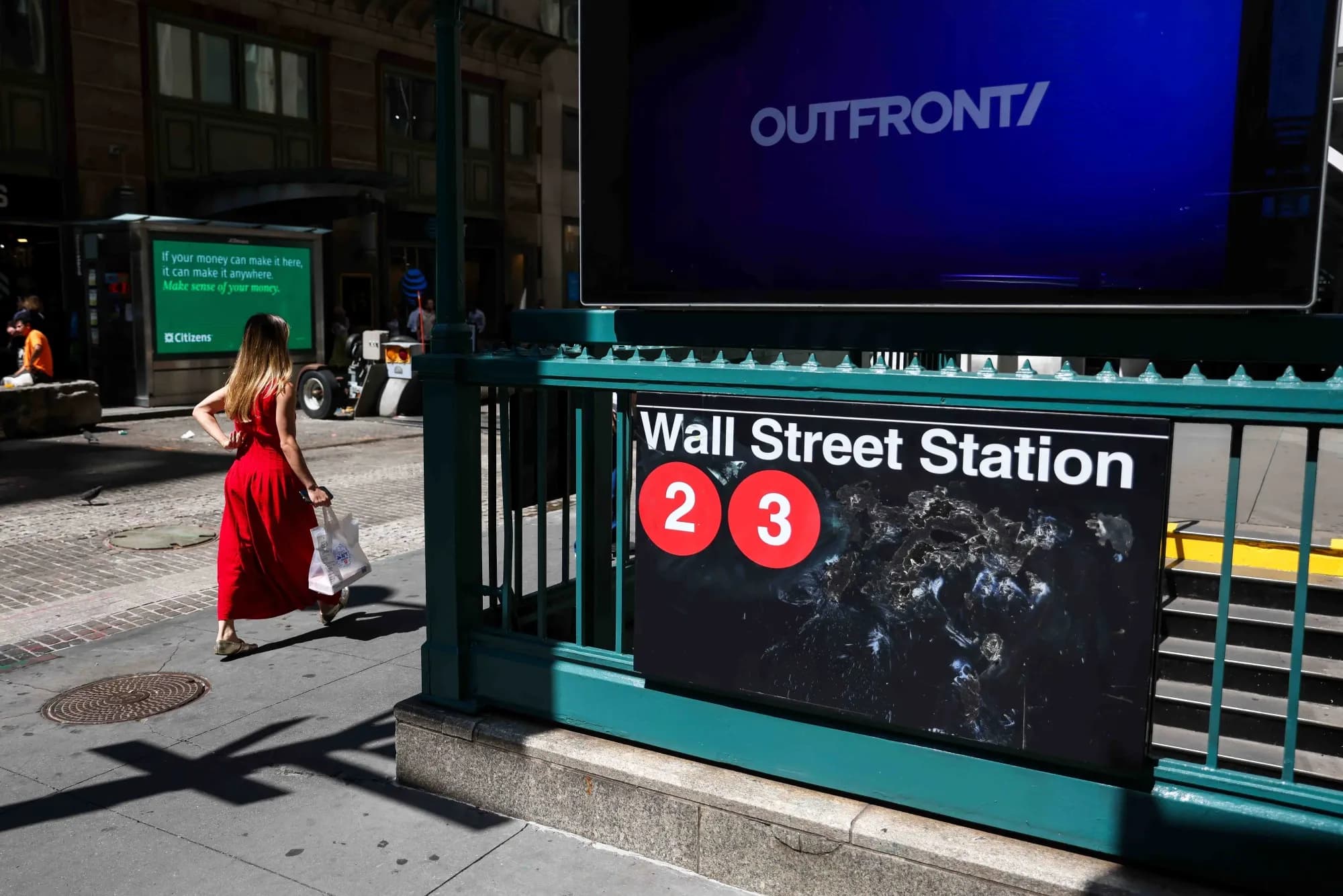 A pedestrian walking past the Wall Street Station subway entrance in New York